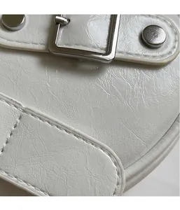Gros plan sur le similicuir blanc texturé avec boucle argentée et coutures précises
