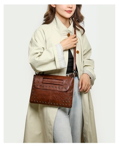 Detail der braunen Vintage-Ledertasche mit dichten Metallnieten und Klappverschluss