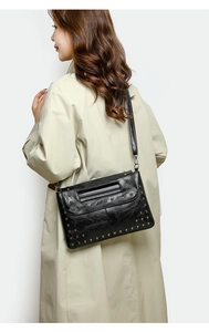 Detail einer schwarzen Lederumhängetasche mit Nieten, präsentiert von einem Model