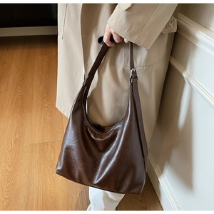 Close-up of dark brown PU leather hobo bag with adjustable strap and silver buckle detail