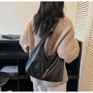 Detail of adjustable silver buckle on black leather shoulder bag with soft hobo design