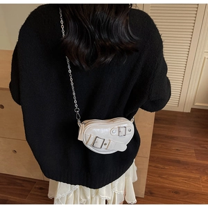 Détail d'un mini sac bandoulière en forme de cœur crème avec boucles et bandoulière chaîne