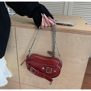 Gros plan d'un mini sac à bandoulière rouge en forme de cœur avec des détails punk argentés