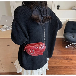 Détail du sac coeur en cuir rouge avec boucles et bandoulière chaîne sur mannequin