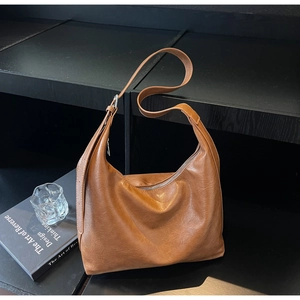 Detail view of a brown vintage hobo shoulder bag on a minimalist display shelf