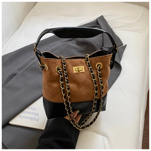 Detailed view of bicolor bucket bag with brown suede, black leather, and quilted pattern
