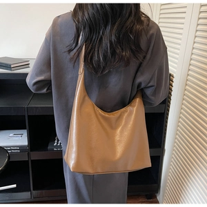 Detailed side view of the caramel brown large capacity leather shoulder bag on a model