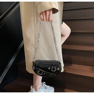 Mini sac noir à chaîne avec boucle métallique porté sur un trench-coat beige élégant