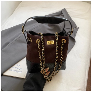 Detailed view of quilted suede bucket bag with gold chain strap and metal lock closure