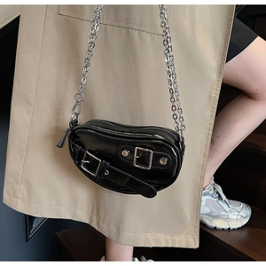 Détail du sac cœur en cuir verni noir avec boucles argentées et bandoulière