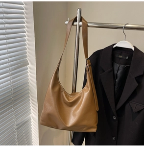 Detail of a brown textured faux leather hobo shoulder bag with adjustable strap