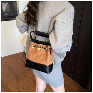 Detail view of quilted bucket bag featuring dual-tone brown suede and black leather finish