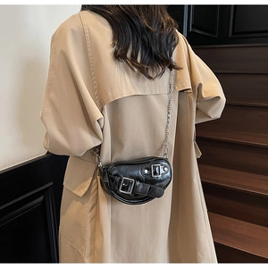 Détail du sac coeur en cuir noir brillant avec boucles métalliques et bandoulière chaîne