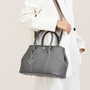 Grey lychee texture tote bag with wide fabric strap carried by a model in a suit