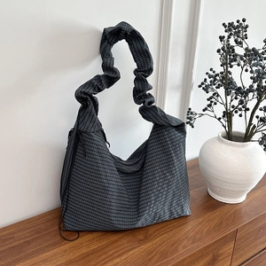 Minimalist black and grey checkered canvas tote bag with unique pleated wide strap on cabinet