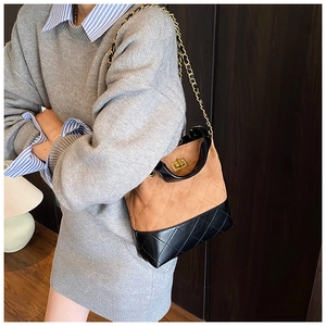 Detail of quilted leather base and chain strap on a chic two-tone bucket bag