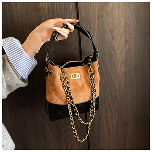 Close-up of contrast bucket bag with suede texture, quilted stitching and gold chain