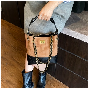 Detail of a brown suede and black leather bucket bag with gold lock and chain strap