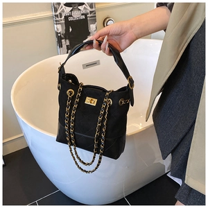 Close-up of black quilted bucket bag with gold clasp and chain strap in luxury setting