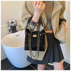 Detailed view of luxury bucket bag with black suede texture and quilted leather chain strap