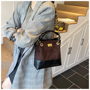 Detail view of quilted bucket bag with golden turn-lock and chain strap on grey blazer