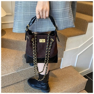 Close-up of matte suede bucket bag with quilted leather base and gold chain strap detail