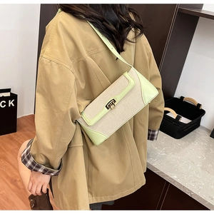 Detail of light green leather and beige canvas crossbody bag with gold metal twist lock
