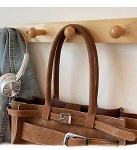 Detail of brown leather tote bag with silver buckle strap and durable top handle