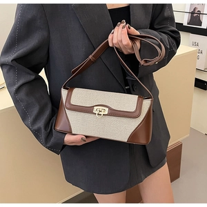 Close-up of retro crossbody bag with beige canvas and brown leather contrast stitching