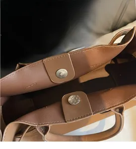Macro detail of the brown leather bag opening featuring dual silver magnetic closures