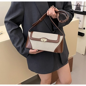 Detail of contrast stitch canvas and brown leather crossbody bag with gold turn-lock