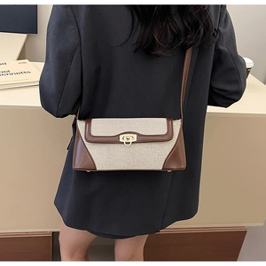 Detail shot of vintage canvas and brown leather crossbody bag worn on a dark blazer