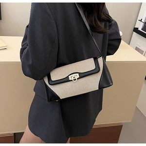 Rear view of model wearing a contrast canvas bag with black leather and gold lock