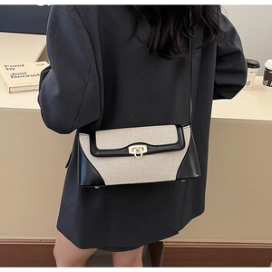 Detail of retro flap crossbody bag with beige canvas, black leather and gold clasp