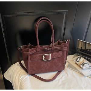 Detail of burgundy faux suede tote bag with metal buckles and detachable shoulder strap
