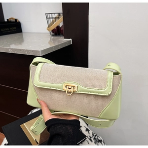 Detail of mint green crossbody bag featuring textured canvas panel and gold ring clasp