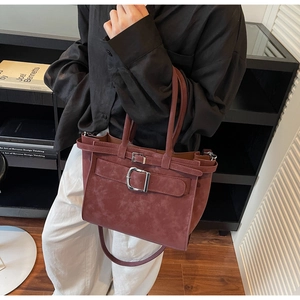 Detail of burgundy vintage tote bag featuring a prominent silver square metal buckle accent