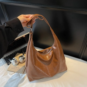 Vintage brown leather hobo shoulder bag with adjustable strap in minimalist office setting