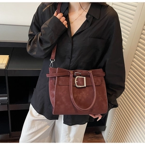 Detail view of burgundy faux suede shoulder bag with decorative silver buckle and strap