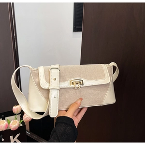 Detail of beige textured fabric and leather patchwork bag with gold buckle closure