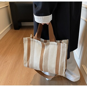 Detail of the woven canvas texture and brown handles on the striped tote bag
