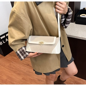 Detail of color-block crossbody bag with gold-tone buckle on khaki trench coat