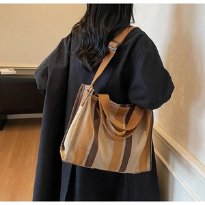 Detail of striped canvas tote bag showing thick woven texture and brown crossbody strap