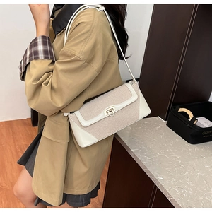 Detail of canvas shoulder bag with white leather trim and golden twist-lock closure