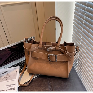Detail of caramel tote bag with decorative buckle and strap in a professional office setting