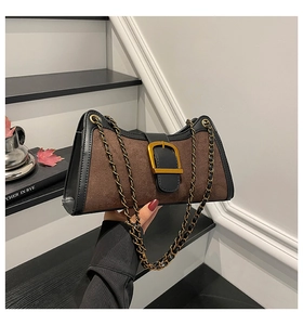 Close-up of vintage brown baguette bag with gold metal buckle and chain on stairs