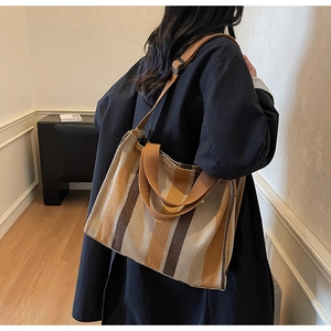 Detail of large canvas tote bag with brown vertical stripes and adjustable shoulder strap