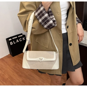 Close-up of cream woven shoulder bag featuring contrast faux leather trim and gold twist lock