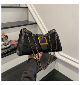 Detail of vintage black baguette bag with gold buckle and chain strap on stairs