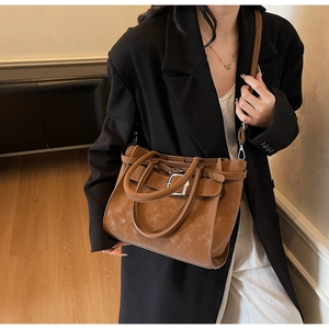 Close-up of vintage brown suede-textured tote bag with silver buckle and leather strap